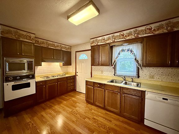Kitchen w/ wall oven, dishwasher, and cooktop.