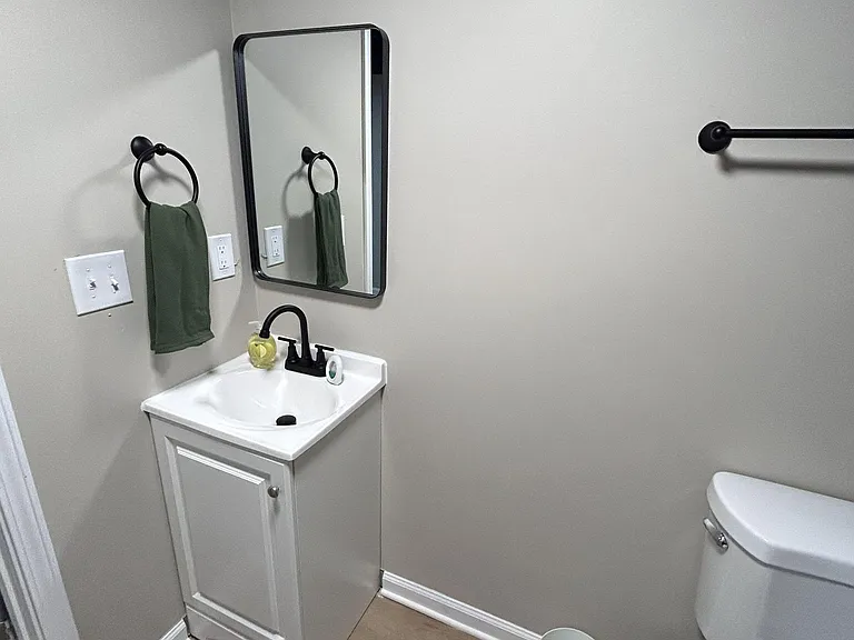 Half bath with pedestal-style vanity, framed mirror, and matte black fixtures for convenient everyday use.
