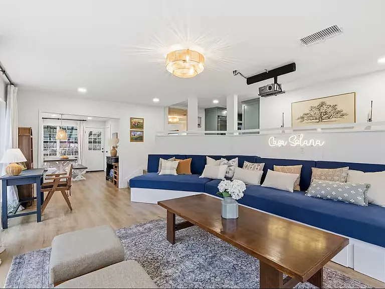 Living room with TV projector and 80" screen and working desk. Couch with drawer makes out into three twin beds.