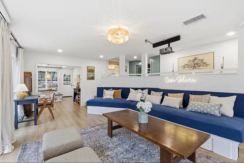 Living room with TV projector and 80" screen and working desk. Couch with drawer makes out into three twin beds. - 6933 Windswept Cir