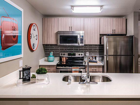 Apartment kitchen with stainless steel appliances, quartz countertops and wood-style flooring.