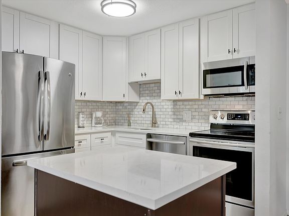 Remodeled kitchen with marble backsplash,, quartz counters and island.