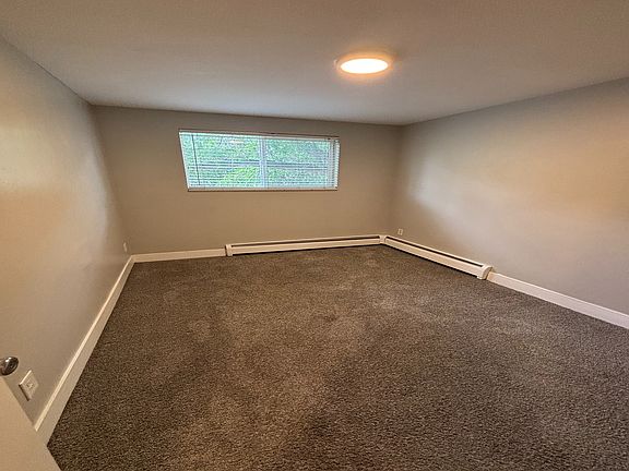 Cozy room with soft carpet flooring and a bright window, perfect for personalization and comfort.