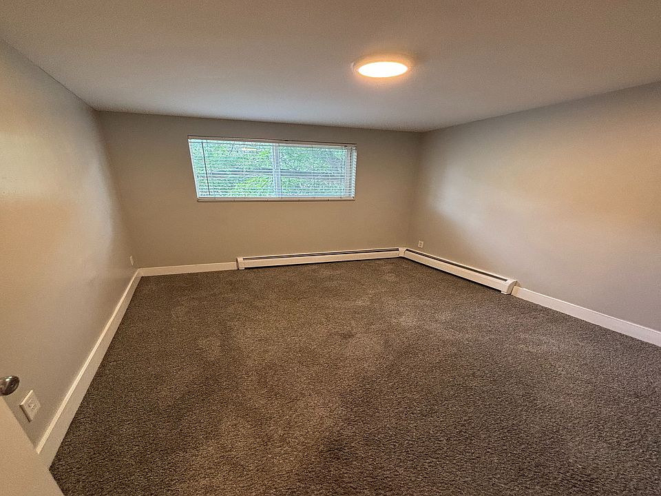 Cozy room with soft carpet flooring and a bright window, perfect for personalization and comfort.