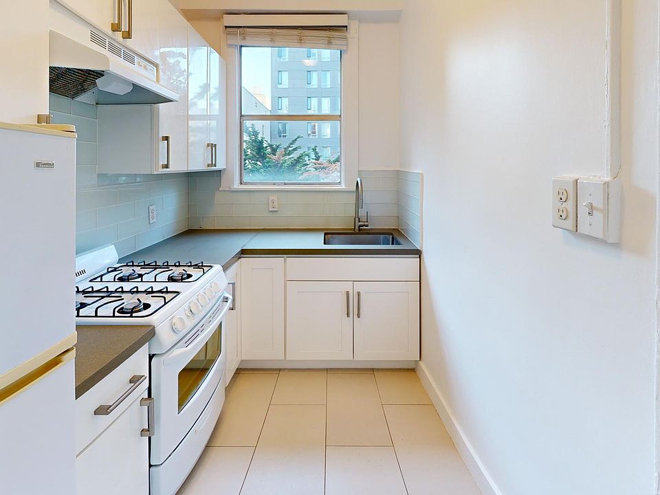 Kitchen with multiple cabinets, refrigerator, stove, range hood, and sink