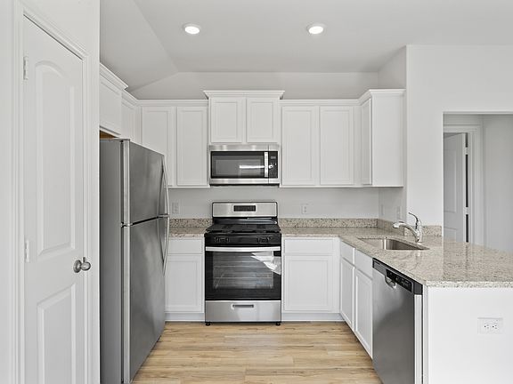 The kitchen features granite countertops and white cabinets
