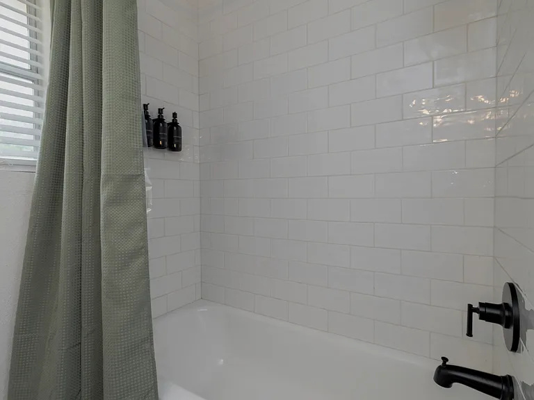 Full bathroom with double sinks and shower-tub combo attached to bedroom 1.