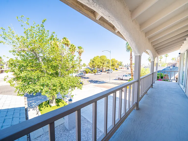 Covered second-story balcony with railing and neighborhood views, providing convenient outdoor space for fresh air.