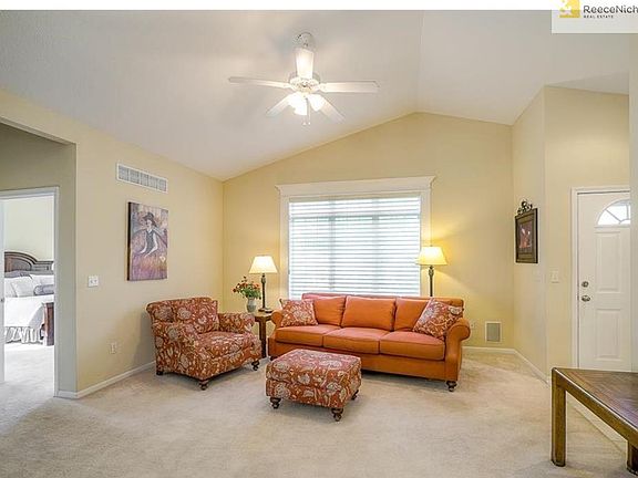 Living room with large window, vaulted ceiling and carpet.