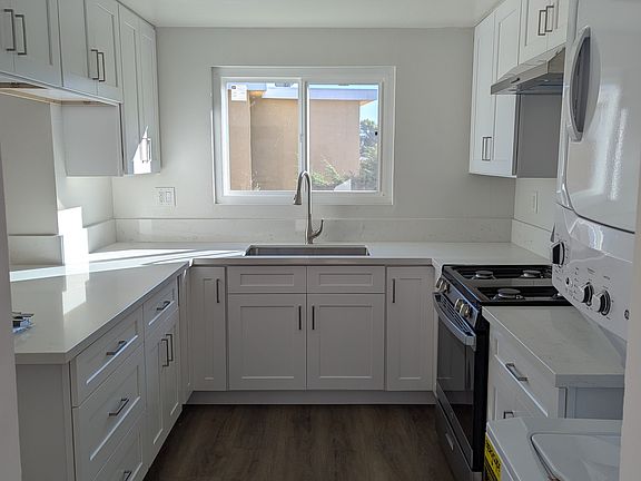 Kitchen with stove/oven, exhaust fan, and laundry washer/dryer.