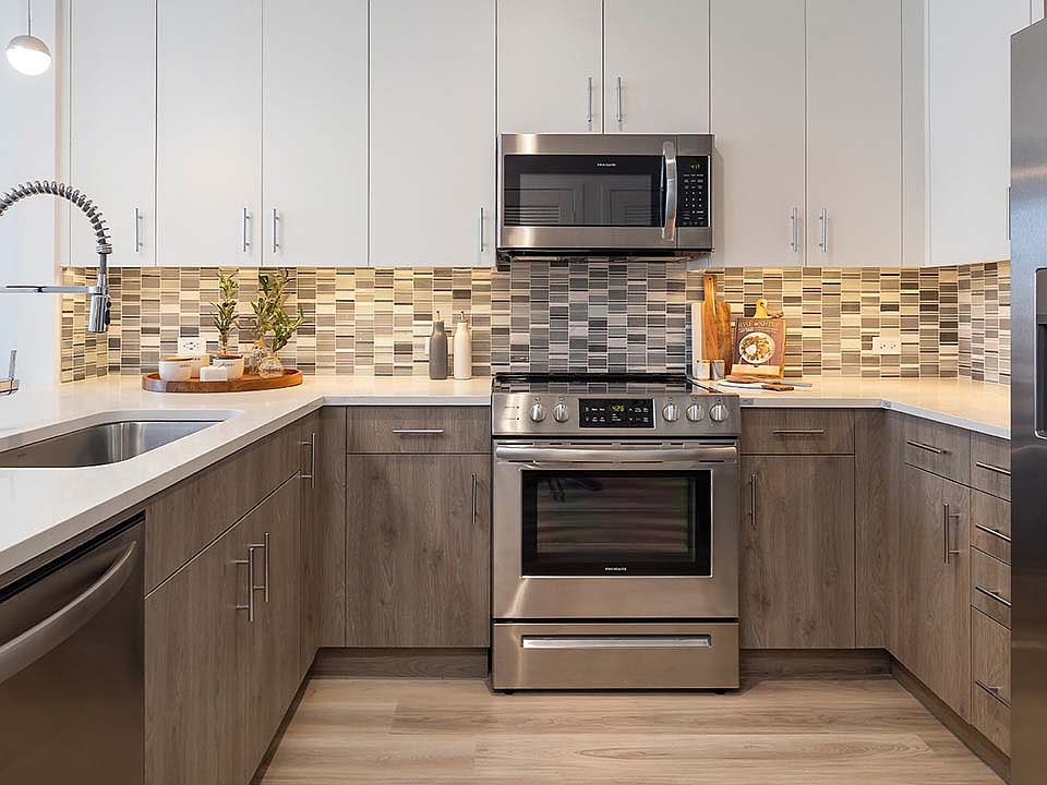 Griffis West Palm apartment kitchen with wood style floor and cabinets, quartz countertops, and stainless steel appliances.