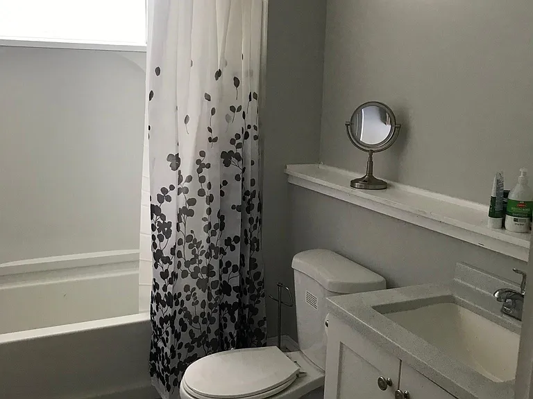 Bathroom on second floor with shower over the tub and large window.