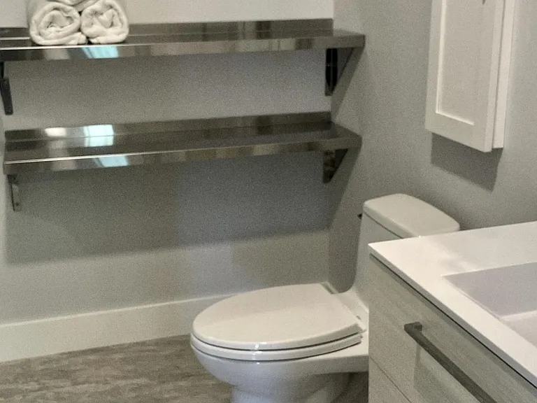 Bathroom with modern toilet, sink, and towel storage