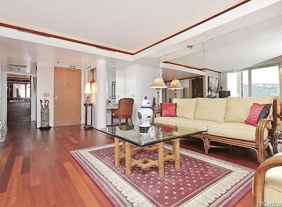 Living room enhanced with hardwood floors, crown molding, custom lighting and mirrors.