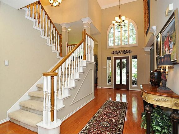 This wide entry area is highlighted by a wrap around staircase and tall windows accented with plantation shutters.