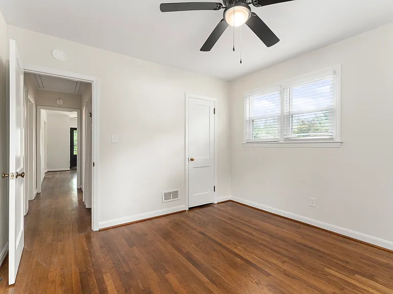 Second bedroom, located in the front of the house, features 3 windows for plenty of light, new ceiling fan, new blinds throughout and newly finished hardwood floors.