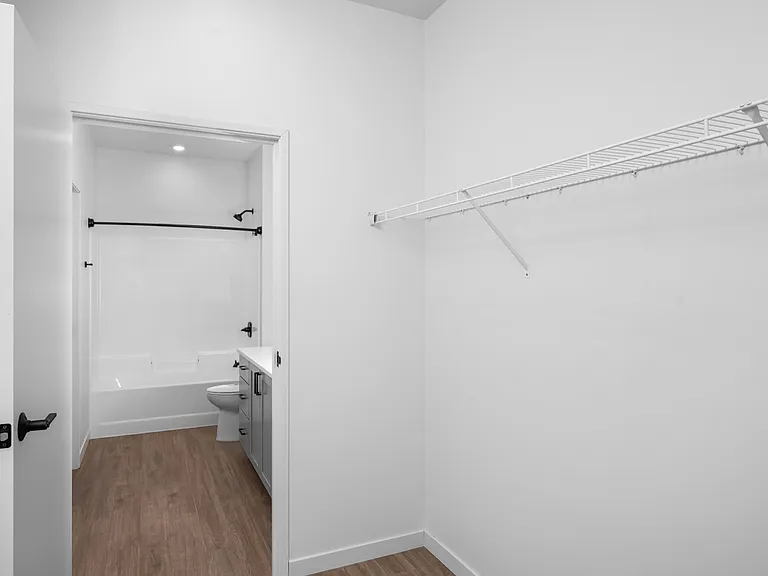 Modern bathroom with sleek fixtures opening into a spacious walk-in closet with wooden flooring and ample shelving. Modern bathroom with sleek fixtures opening into a spacious walk-in closet with wooden flooring and ample shelving.