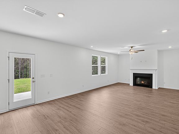 Expansive living area with gas fireplace, hard-surface flooring and tree-lined backyard views