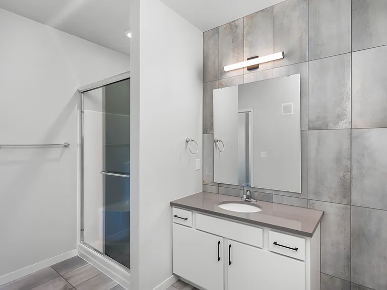 Modern bathroom with sleek vanity, large mirror, and glass-enclosed shower. Elegant wall tiles accentuate the contemporary design. Modern bathroom with sleek vanity, large mirror, and glass-enclosed shower. Elegant wall tiles accentuate the contemporary d