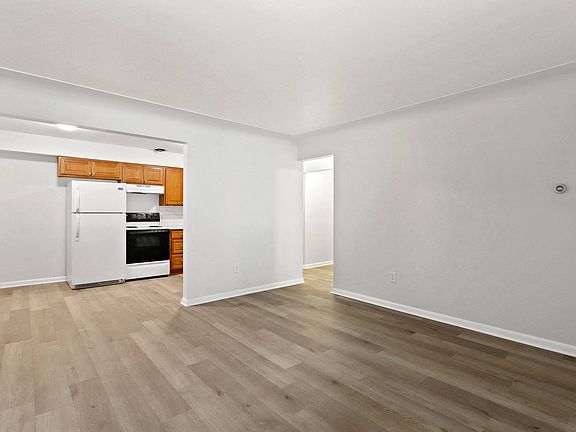 Bright and inviting kitchen area with wooden cabinetry, white appliances, and elegant flooring, perfect for a modern lifestyle.