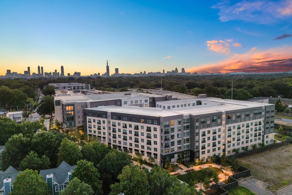 Chic urban apartment complex with modern design, surrounded by lush greenery and offering stunning sunset views of the city skyline.