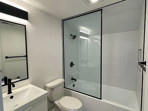 Stylish full bathroom with modern tile, glass shower enclosure, and matte black finishes.