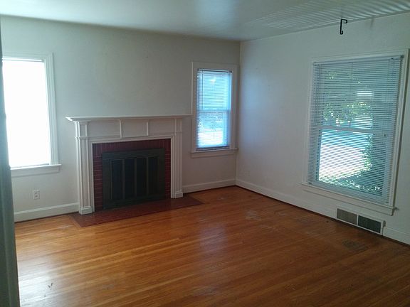 Big living room with lots of light, hardwood floors, decorative fireplace.