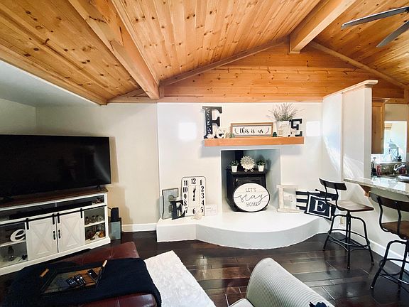 Family room with vaulted ceiling fireplace and mantle. Open to kitchen with eating bar.