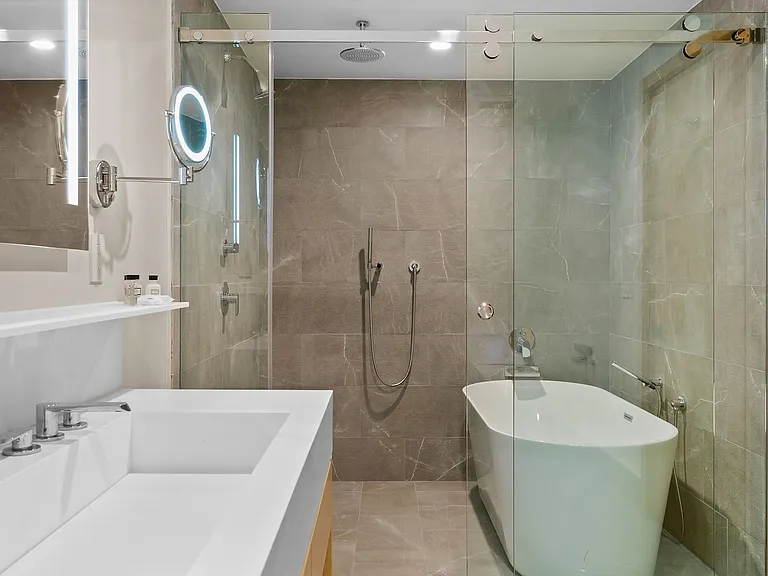 Luxurious bathroom equipped with LED mirrored lighting, a walk in shower and a deep soaking tub