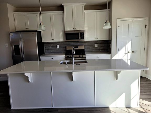 Large breakfast bar with pendant lighting. Stainless appliances and glass tiled backsplash. Large Pantry closet