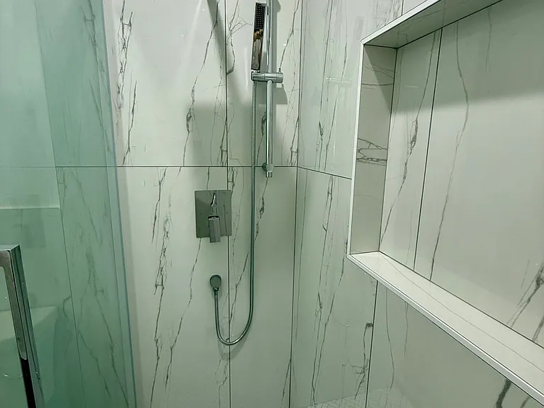 High end bathroom complete with a beautiful tile floor, shower niche to hold all your shower supplies and a rain shower head.