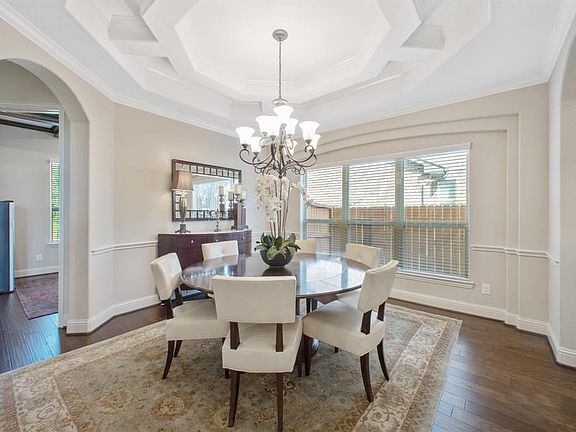 Formal dining with crown molding, chair railing, wood floors, arched entries and stunning designer ceiling