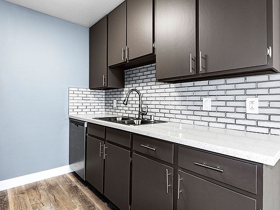 White tiled kitchen with stainless steel fixtures.