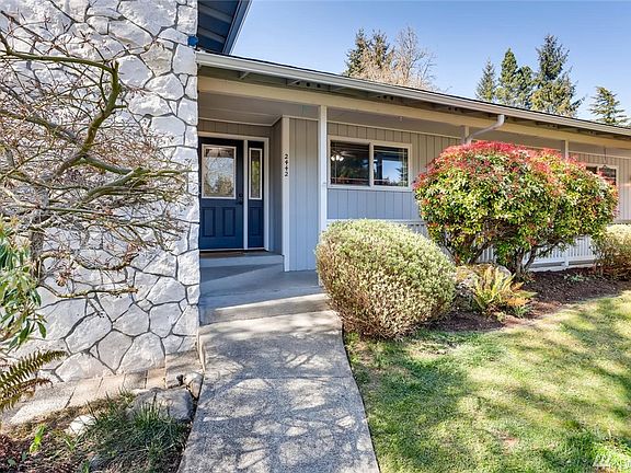 Covered walkway from the garage to the front door and a path from the sidewalk to the front door. The path in front of the stone leads to a private patio area.