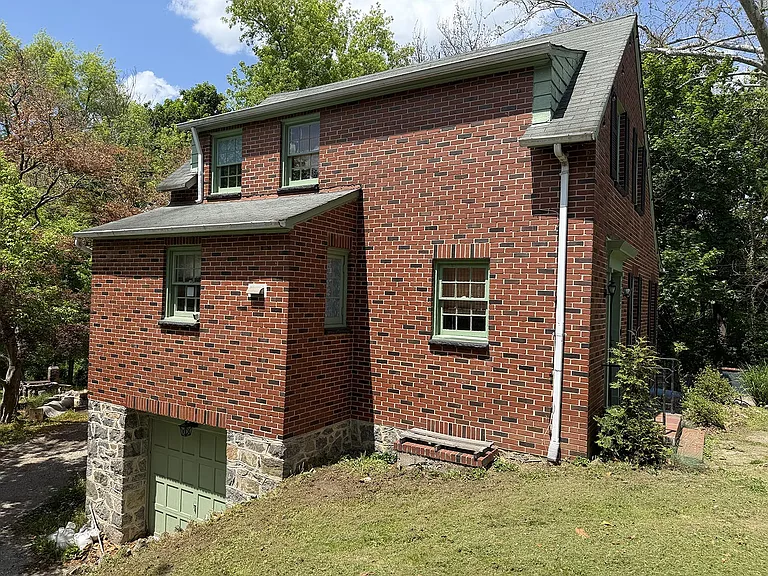Stone steps lead to a 1-car garage and parking pad in the rear.