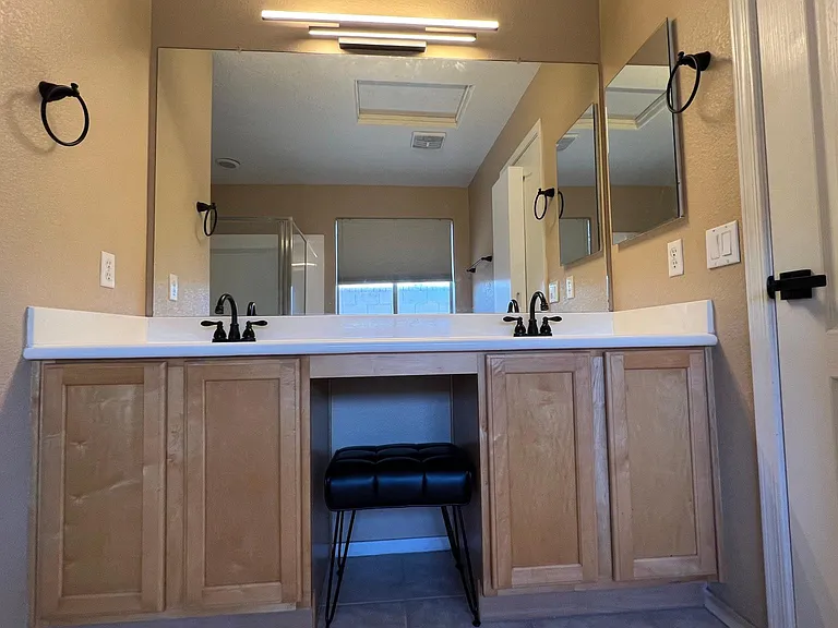 master double sinks with vanity and bench chair for sitting to put on contacts lenses, make-up, trimming beard, flossing, etc.
