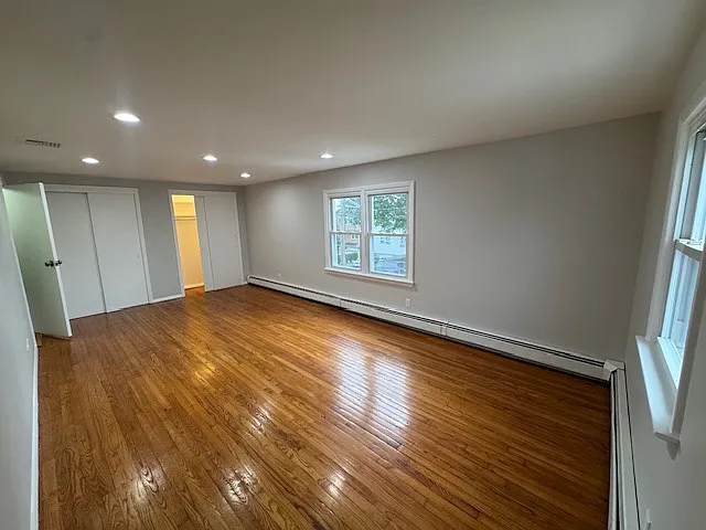 Bedroom 3 / Primary: Spacious and versatile room with ample space to accommodate a comfortable bedroom setup and a dedicated work-from-home area. Features abundant natural light, beautiful hardwood floors, and a closet for convenient storage.