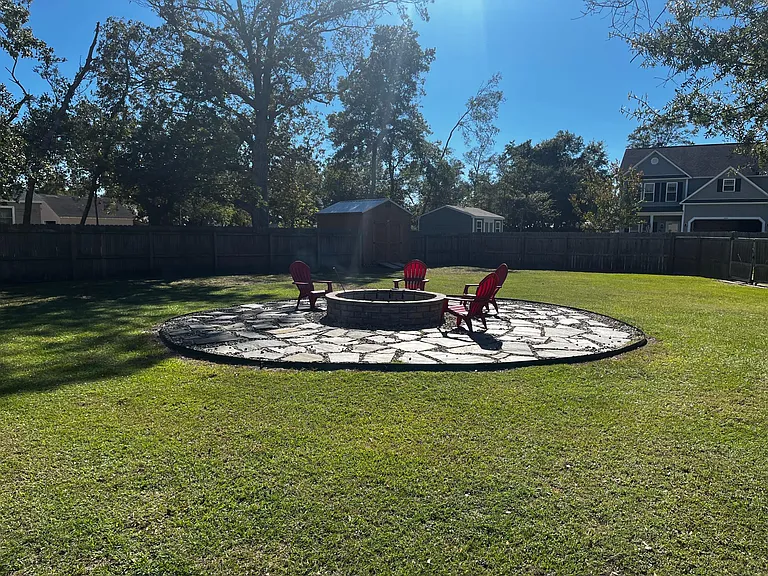 Spacious backyard centered around the impressive stone firepit and seating area.