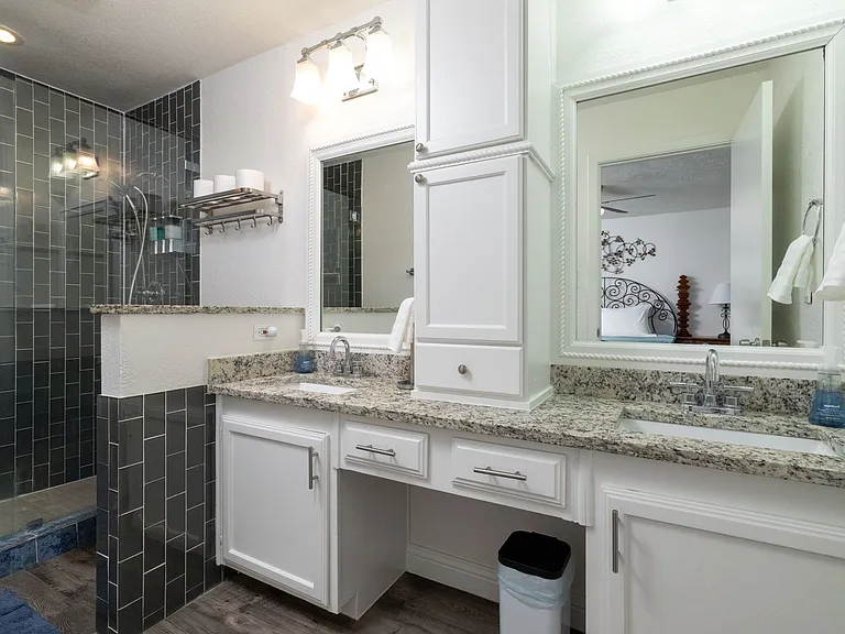 Bathroom 1 is attached to the primary bedroom featuring a walk-in shower stocked with shower gel, shampoo, and conditioner, along with a double sink vanity_offering a clean, refreshing space to start or end your day.