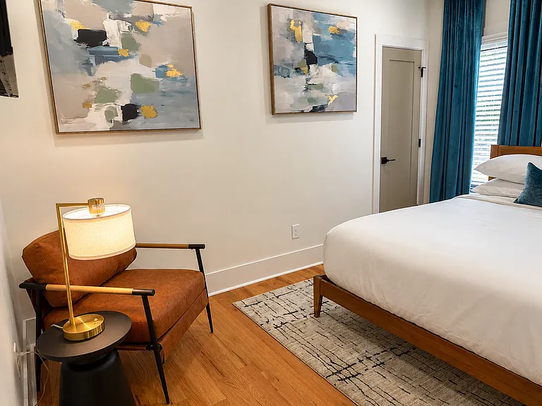 Queen bedroom with calming blackout curtains, smart TV, bedside charging, plush bedding, spacious walk-in closet, seating, and a private, restful suite-style feel.