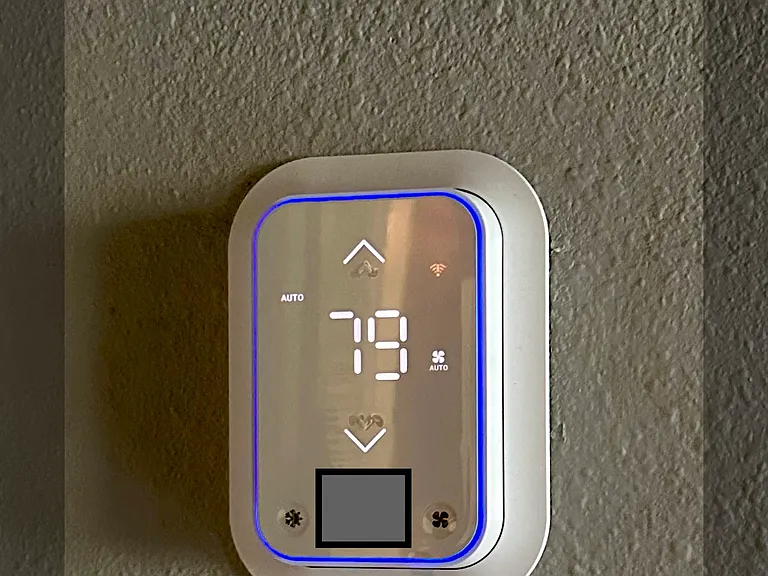 Wireless programmable thermostat located in hallway.