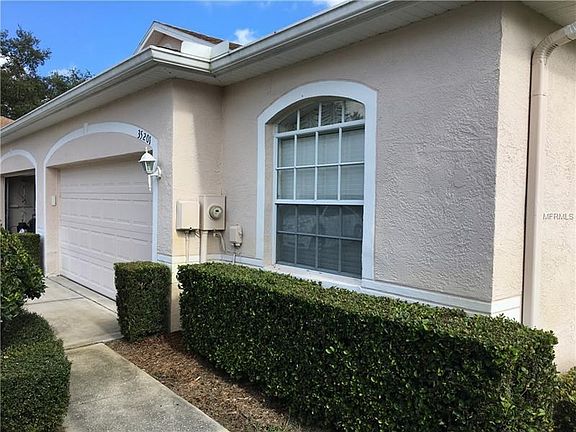 Front of home showing Garage Dbl. Door, Landscaping hedges & custom window.  Also shows gutters & dn. spouts