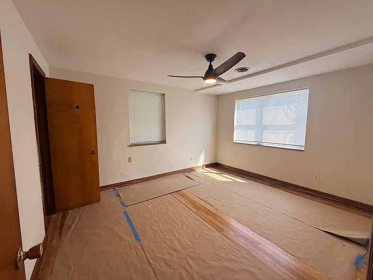 Bedroom 1 with 2 closets and protective paper on newly refinished hardwood floors