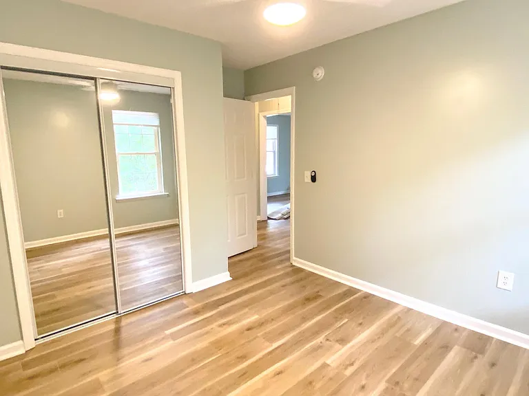 Third bedroom with mirrored closet doors and a window facing the back yard.