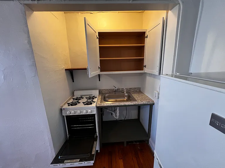 The compact kitchen includes a gas range, refrigerator, with storage space above and below.