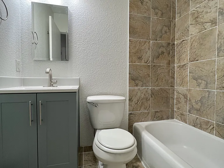 Bathroom shower/tub with medicine cabinet and vanity for storage.