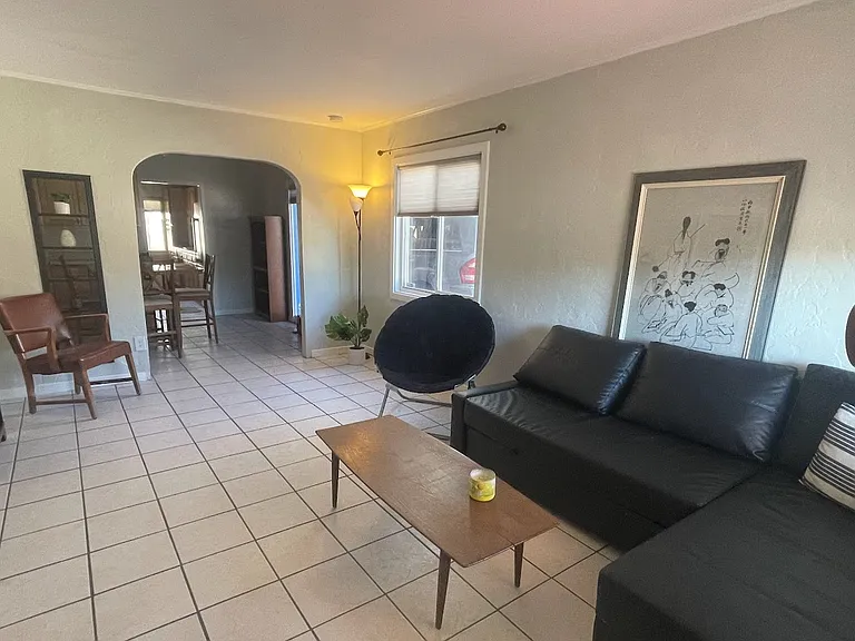 Living room with wall mounted flat screen TV and leather couch that converts into a bed.