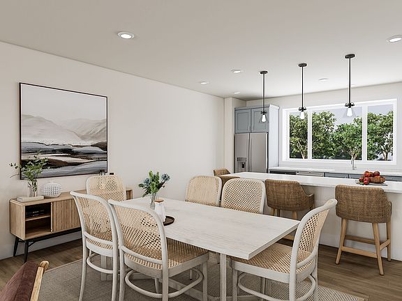 A modern and cozy dining area with a wooden table, wicker chairs, and a large window overlooking a l