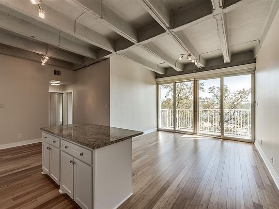 Same view unstaged - this open floor plan boasting gleaming bamboo floors with lofty exposed concrete ceilings.