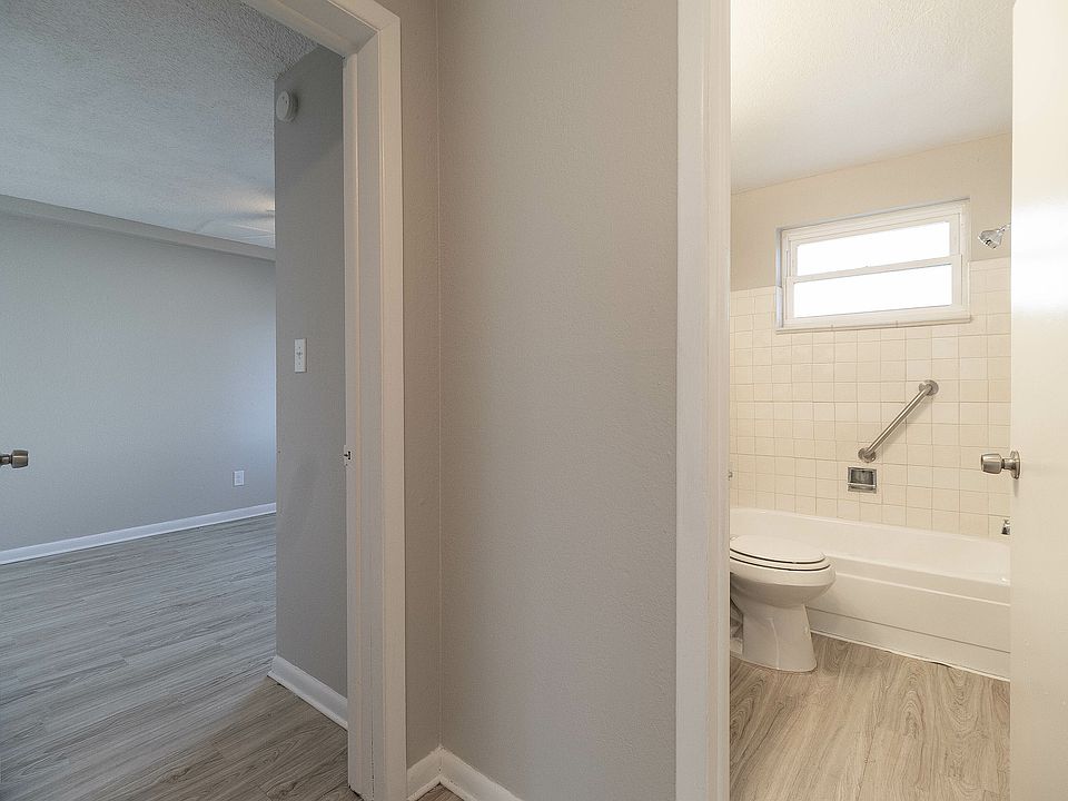 Inviting hallway view featuring a modern bathroom and a spacious bedroom with elegant wood flooring.